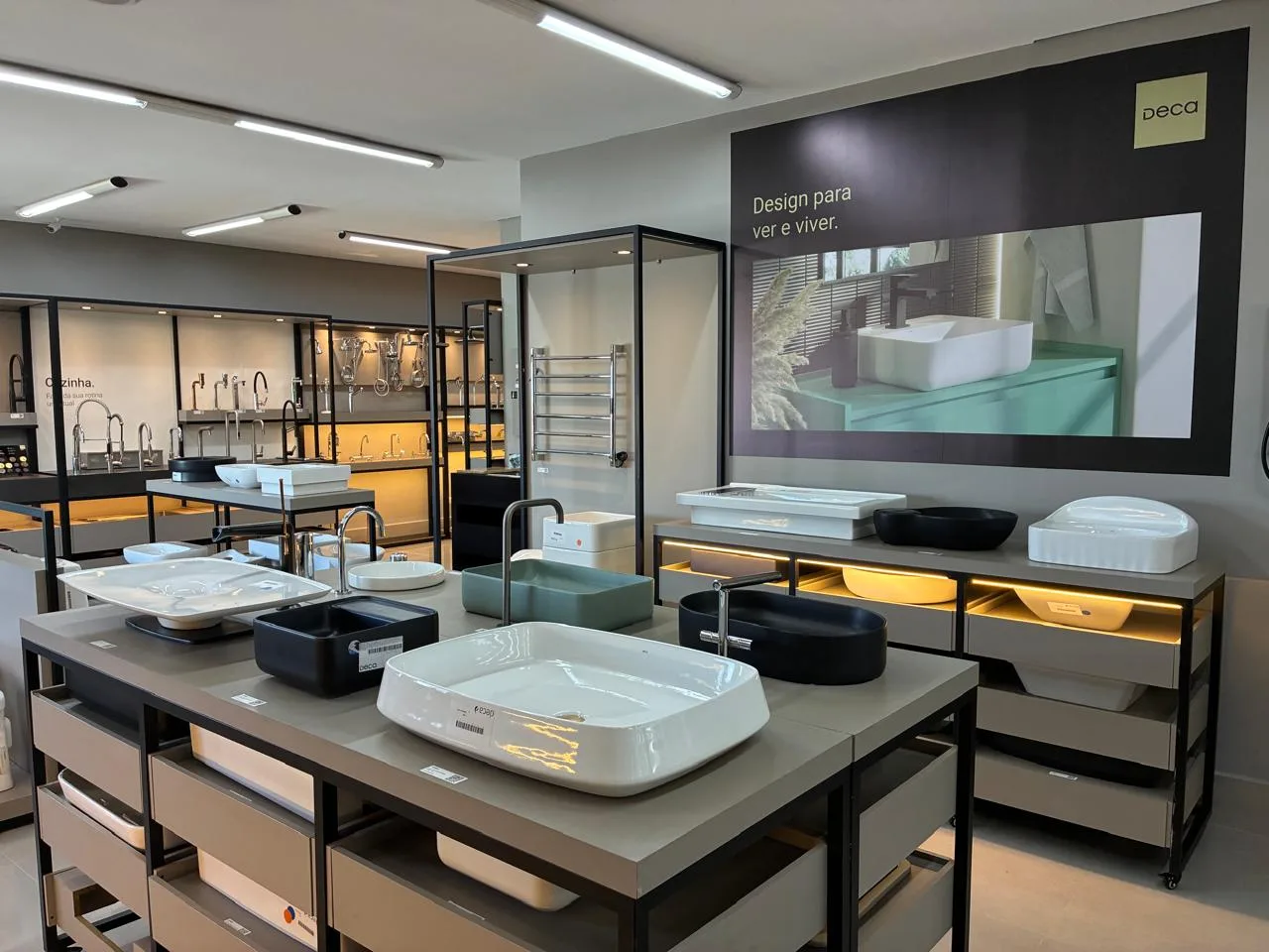 Área de louças e metais Deca no showroom da Linha Direta, com cubas de apoio e torneiras expostas